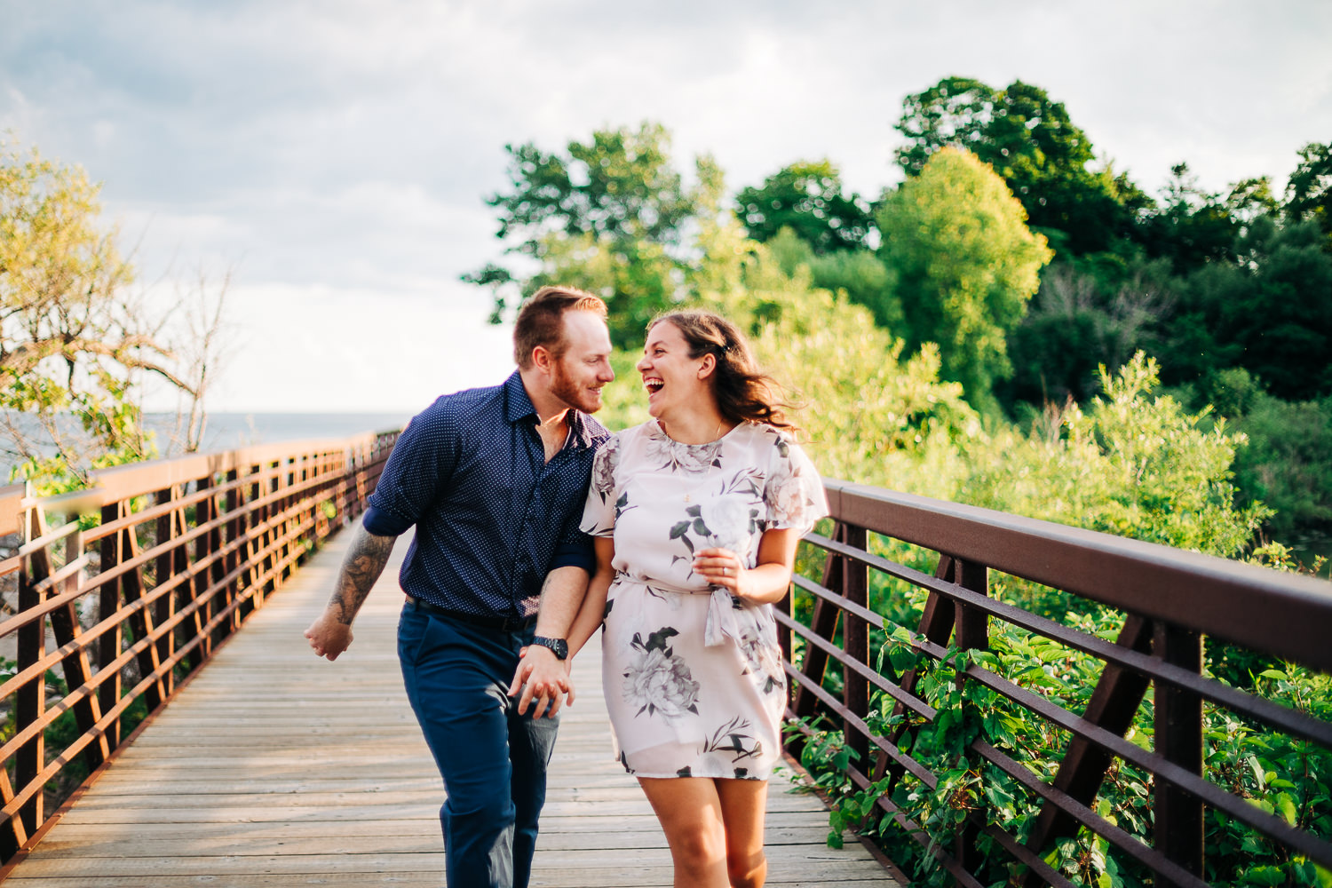 Playful couple laughing while prancing along a boardwalk