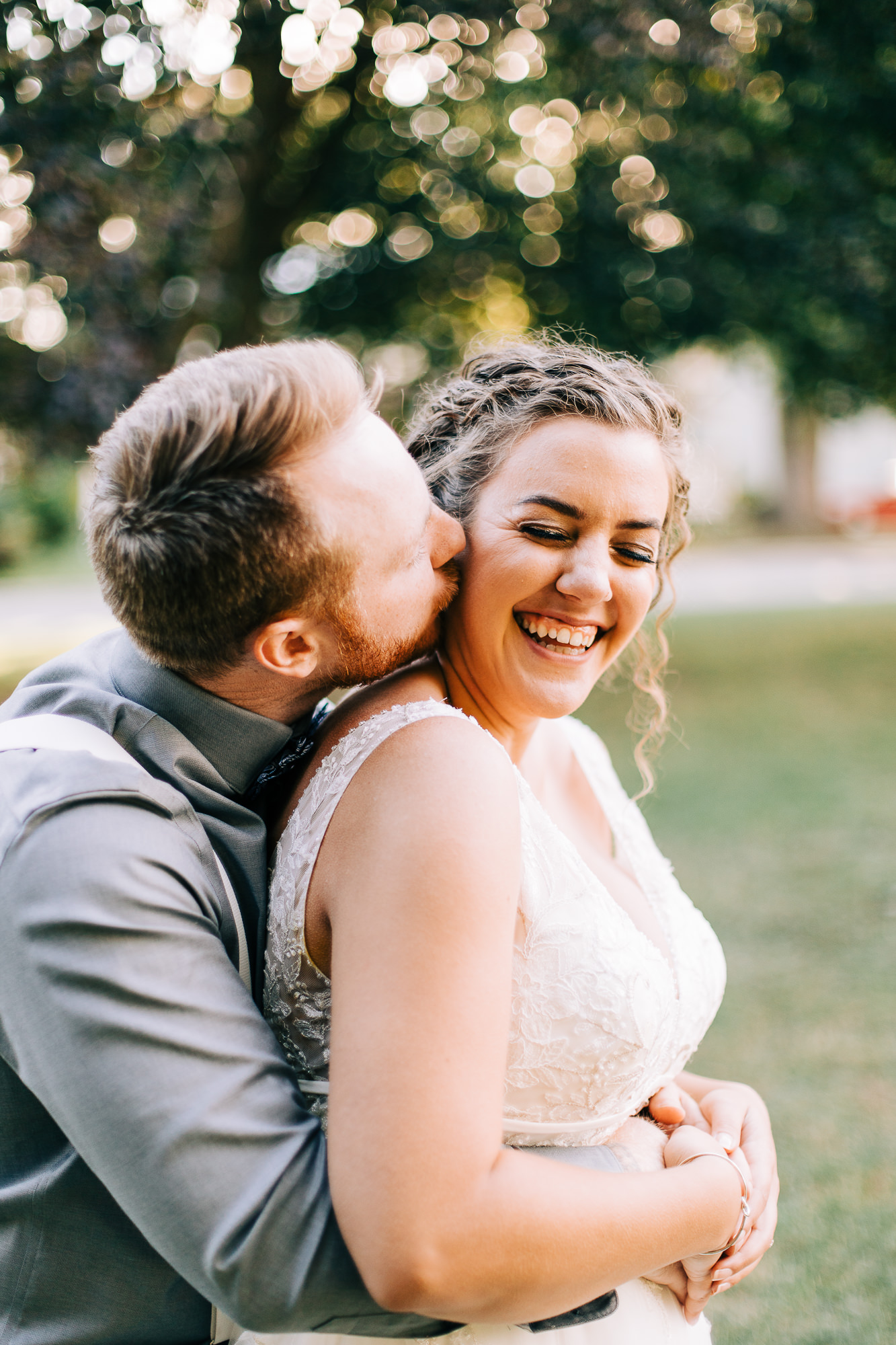 Bride embraces groom with a little laugh in a pine forest